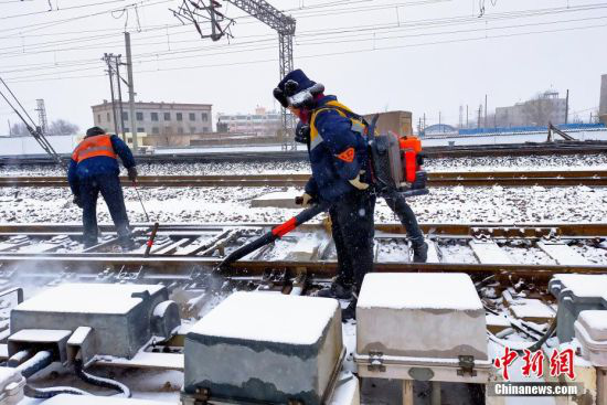 28日,受冷空气影响,甘、宁两省区局部迎来今年春节后的第一轮降雪。图为铁路职工清扫道岔积雪。 王喜栋 摄