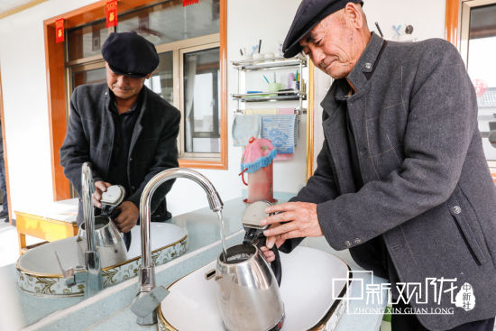 图为古浪县干城乡富民新村村民徐生喜正在接自来水。