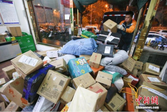 资料图:物流业工作人员给快递卸车