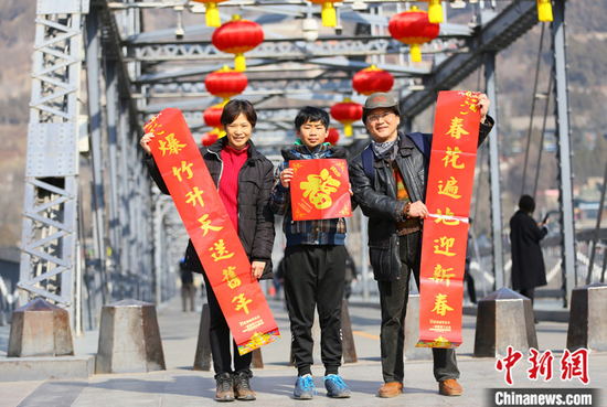 2021年春节期间,台湾夫妻杜书亿和王梅芬带着孩子一起在兰州中山铁桥前合影留念。 中新社记者 高展 摄