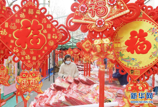 1月31日,顾客在永靖县刘家峡镇一市场挑选节庆饰品。新华社发(史有东 摄)