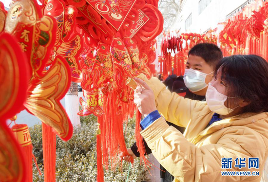 1月31日,顾客在永靖县刘家峡镇一市场挑选节庆饰品。新华社发(史有东 摄)