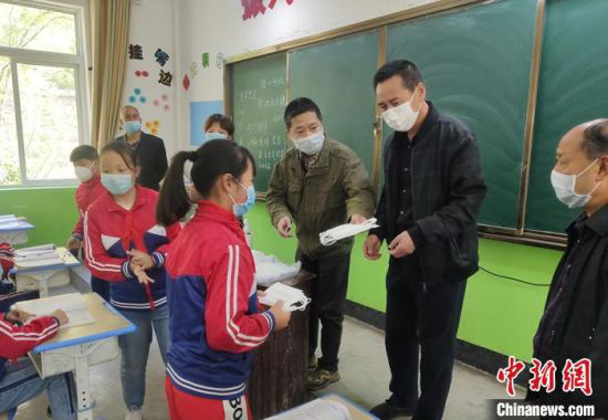 图为冯继(右三)和老师给学生发放防疫物资。(资料图)受访者供图