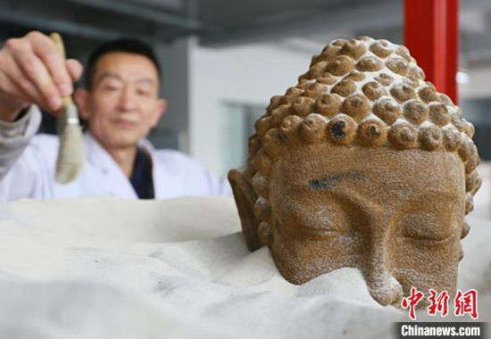 4月初,位于兰州高新区的甘肃伯骊江3D打印科技有限公司内,56岁的“玩”沙人潘炳庆清理由沙子打印成的佛像模型。 高展 摄