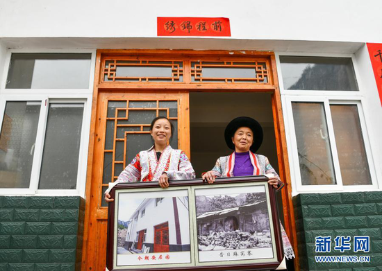 2月20日,在贵州省毕节市黔西县新仁苗族乡化屋村麻窝寨易地扶贫搬迁集中安置点,苗族女孩王代玉(左)与母亲杨文梅在自家新房前展示易地扶贫搬迁前后的对比照片。近年来,化屋村在实施易地扶贫搬迁的同时,大力发展特色种植、养殖、旅游等产业,村里迎来跨越式发展。 新华社记者 杨文斌 摄