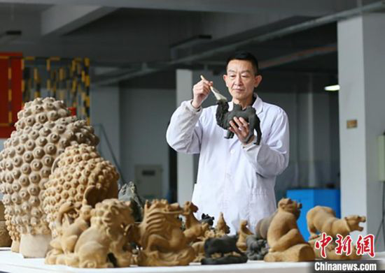 图为潘炳庆和仿制文物及文创产品的合影。 高展 摄