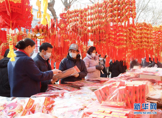 1月31日,顾客在永靖县刘家峡镇一市场挑选节庆饰品。新华社发(史有东 摄)