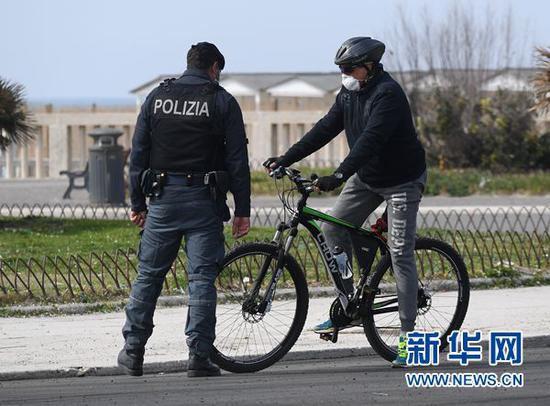 3月21日,在意大利罗马附近的奥斯蒂亚,警察查验一名骑行者。新华社发(阿尔贝托•林格利亚摄)