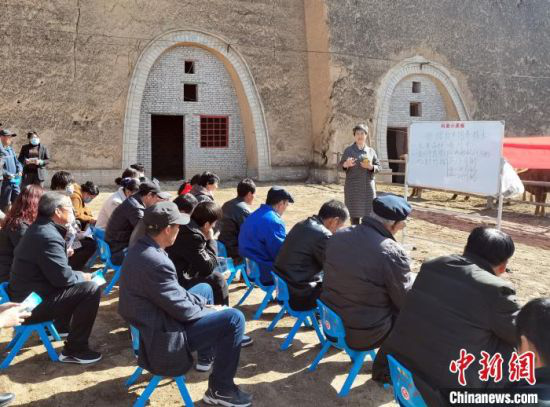 日前,在甘肃平凉市崇信县甘庄村窑洞养牛基地的牛舍旁,养殖户们围在一块“科普小黑板”前听课。 关惠文 摄