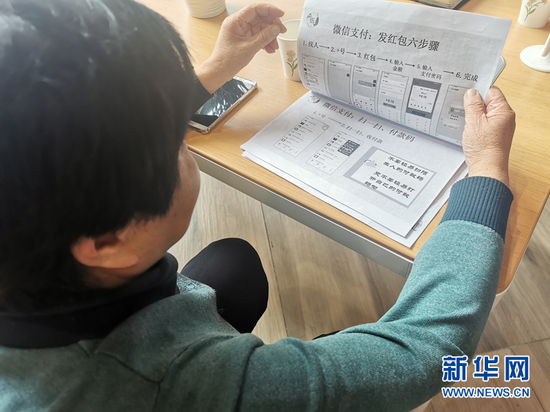 郑辉芳在翻看有关智能手机使用的教材。新华社记者 何问 摄