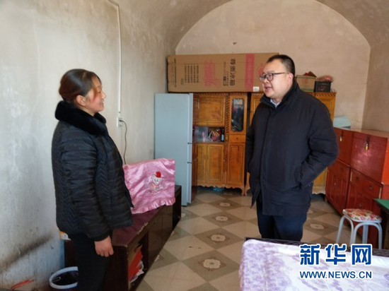 邱军(右)和华池县南梁镇高台村村民张应芬商议产业发展情况(2019年1月22日摄)。新华社发(华池县委宣传部供图)