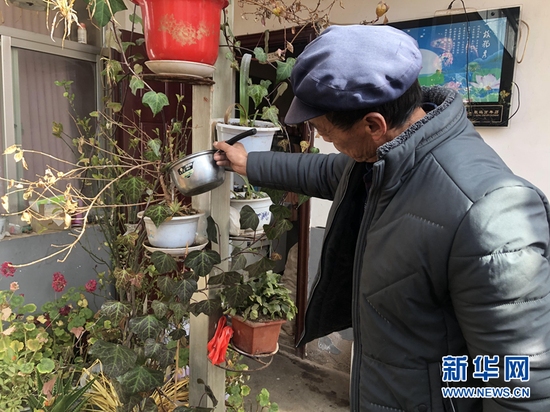 李有录在家里给花浇水。 新华社记者 张文静 摄