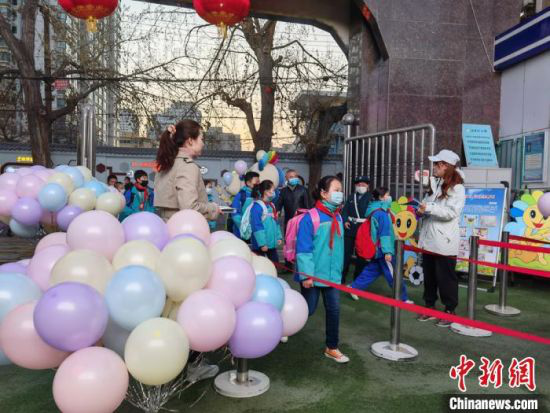图为老师们在校门口布置气球、吉祥物欢迎学生归校。 刘玉桃 摄