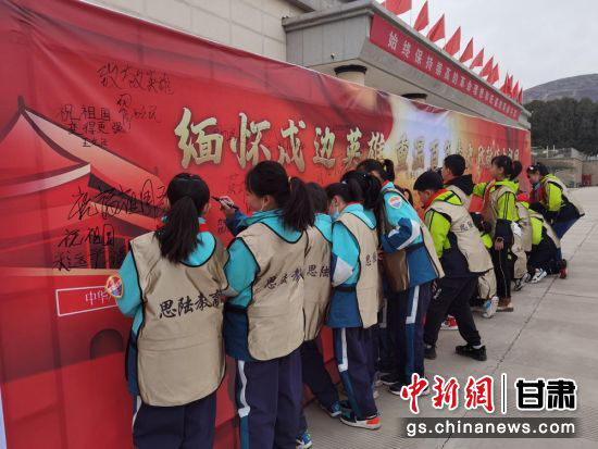 图为小学生在签名墙上签名。