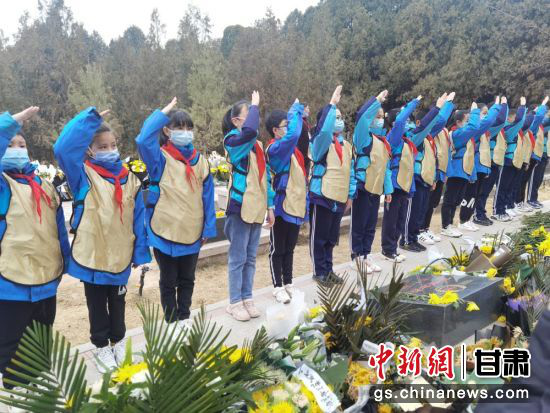 图为小学生向烈士敬队礼。