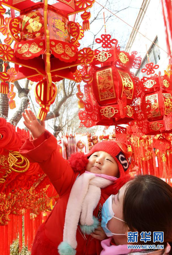 1月31日,家长带着孩子在永靖县刘家峡镇一市场挑选节庆饰品。新华社发(史有东 摄)