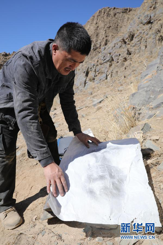 3月22日,杜成峰在甘肃省张掖市肃南裕固族自治县榆木山将做好的拓片从岩画上取下。新华社记者 杜哲宇 摄