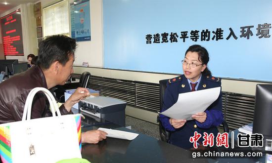 图为甘肃省市场监管局工作人员为民众讲解政策。