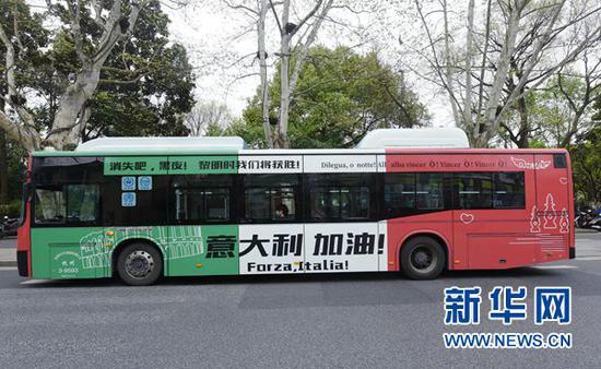 3月24日,乘客在杭州一公交车站乘坐写有“意大利,加油”祝福语的公交巴士。新华社发(龙巍 摄)