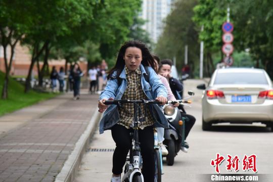 一名骑自行车上课的学生穿着长袖衬衫和牛仔外套。 王以照 摄