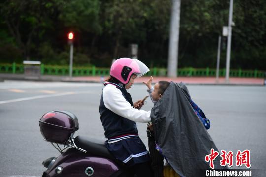 一位接孩子放学的市民穿着厚实的外套。 王以照 摄