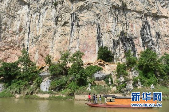 (游客在崇左市宁明县明江乘船观赏花山岩画。新华社记者 周华 摄)