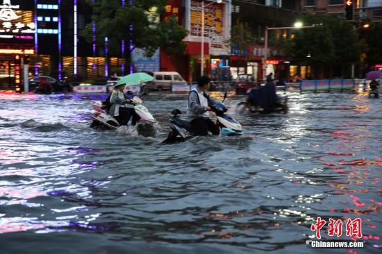 资料图:市民在雨中艰难出行。中新社发 魏东升 摄
