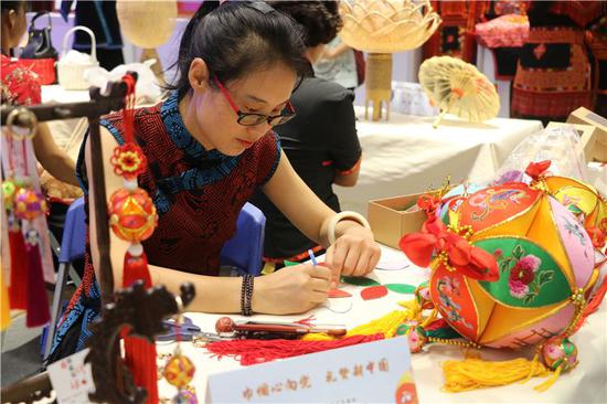 展会上,一位绣娘现场展示绣球制作