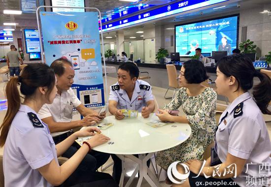 桂平市办税服务厅内税务人员正在向纳税人宣传推广“减税降费红利账单”查询新功能