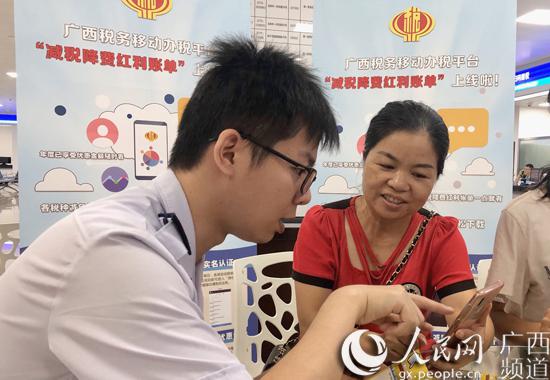 玉林市办税服务厅里,税务工作人员向前来办理涉税业务的纳税人介绍“减税降费红利账单”