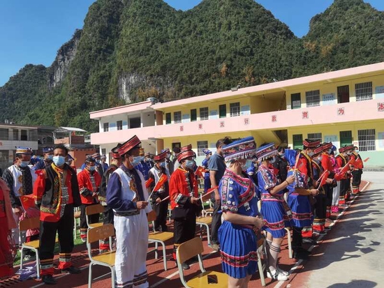 广西南宁市马山县古寨瑶族乡干部群众身着民族盛装，在古棠村古棠小学操场上，集体收看党的二十大开幕式。受访者供图