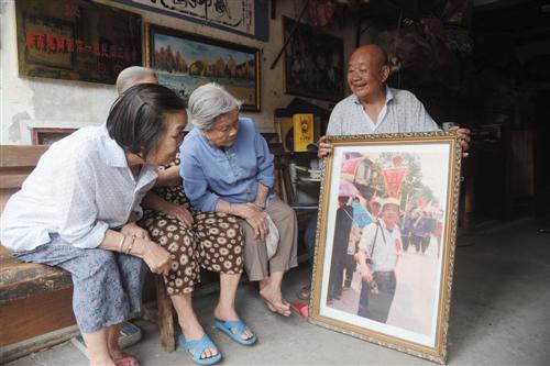 苏荣森(右一)拿出上世纪80年代“水上民歌队”去武鸣参加“三月三”壮族歌节巡游活动的留念照片,勾起了大家的回忆 记者 刘增璇 摄