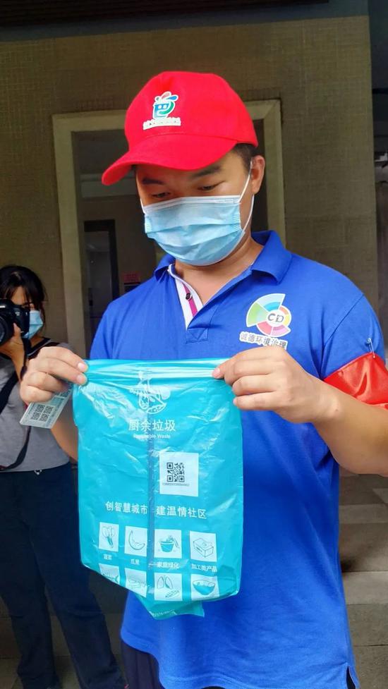 图为工作人员手拿二维码垃圾袋