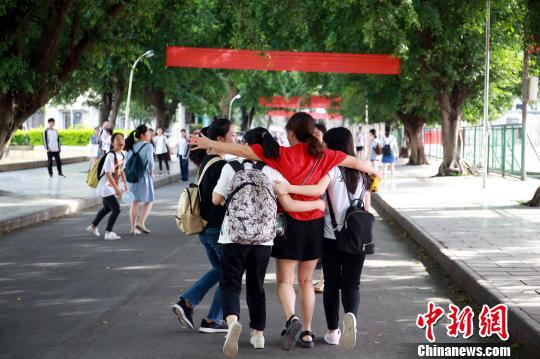 一名穿着红色衣服的老师抱着学生出发去考场。 朱柳融 摄
