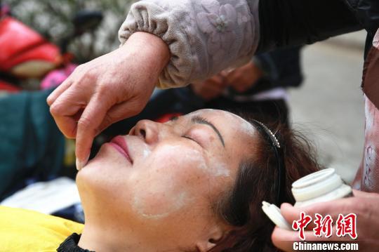 绞脸师给顾客脸上涂谷壳灰。 朱柳融 摄