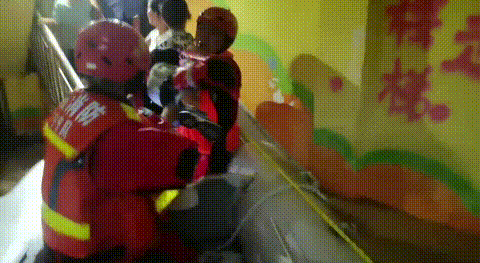 消防救援人员接力将孩子抱上冲锋舟