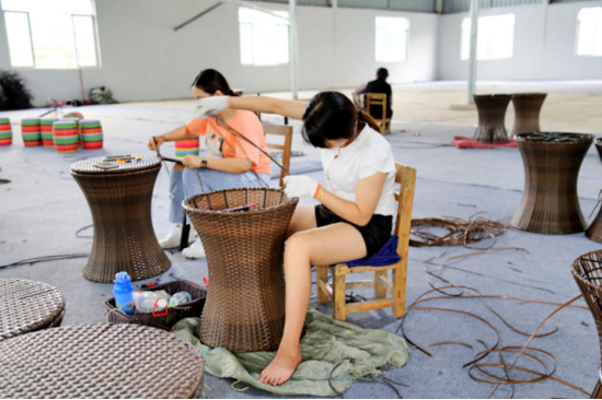 图为扶贫车间女工编织酒桶