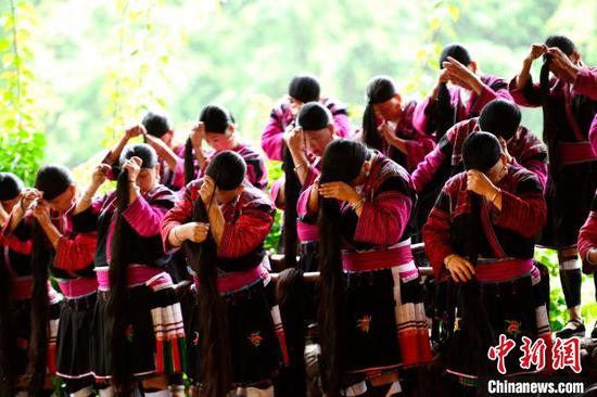 9月26日，在广西桂林市龙胜各族自治县龙脊镇黄洛瑶寨歌舞场，瑶族群众在表演长发梳妆。　潘志祥　摄