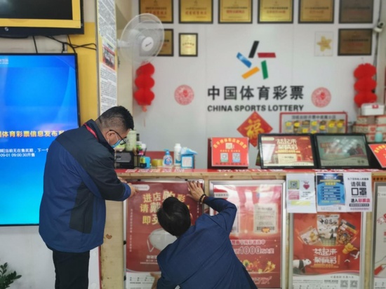 图为 网点代销者在布置开市宣传海报