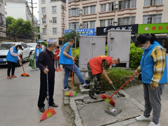 图为：志愿者用钳子捡拾卫生死角垃圾