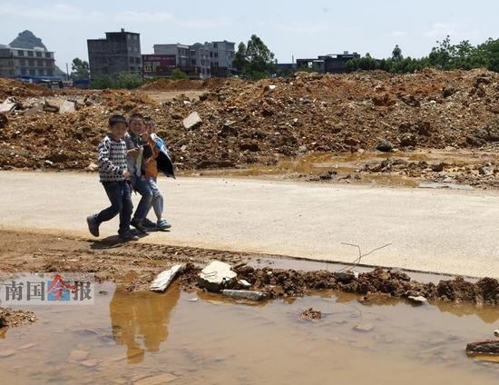 昨日上午，柳江县进德镇三千村，几名儿童从数十亩的倒土场旁经过。这里的大量泥土侵蚀着河道。 记者 张存立 摄