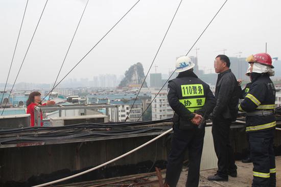 民警和消防官兵正劝庞某回到安全地带,中间站立的男子为其丈夫王某。 今报记者 石红星摄