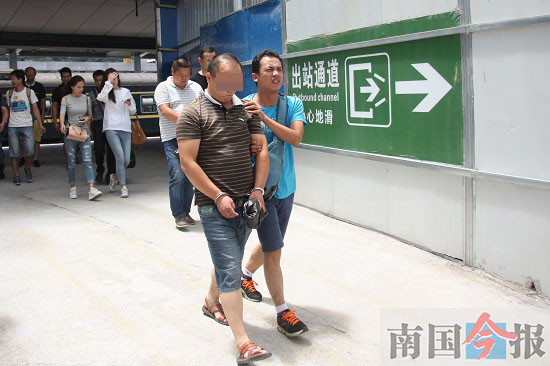 便衣民警将调包诈骗嫌疑人(左)押出柳州火车站。记者 钟华 摄