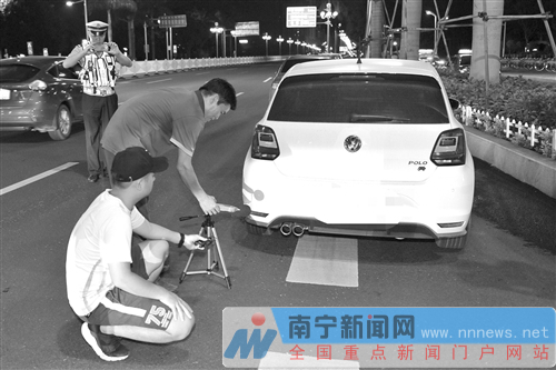 夜查行动中,环保部门工作人员对车辆尾气排放噪声进行测量。(邱祥星 摄)