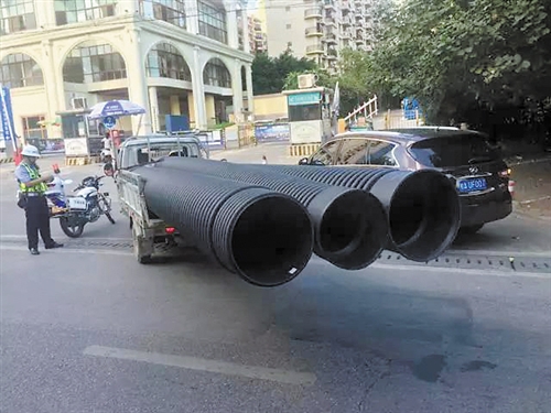 三轮货车所载货物违规超长,被交警查处。