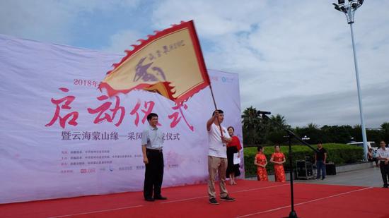 蒙山县人大常委会主任何健向采风团作家代表杨克授旗