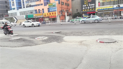 市民骑车路过多个凸出地面的井盖 本报记者 韦薇 摄