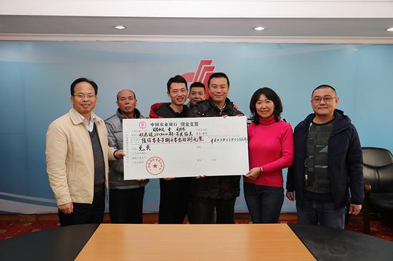 广西福彩中心副主任梁卫(左一)向部分中奖代表颁发奖金支票(王云涛摄)