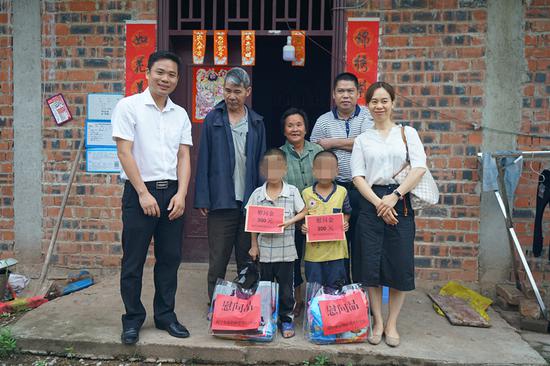图为:市福彩中心工作人员为孤儿家庭送慰问金和慰问品