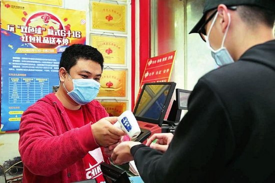 (图2投注站业主为彩友测量体温)